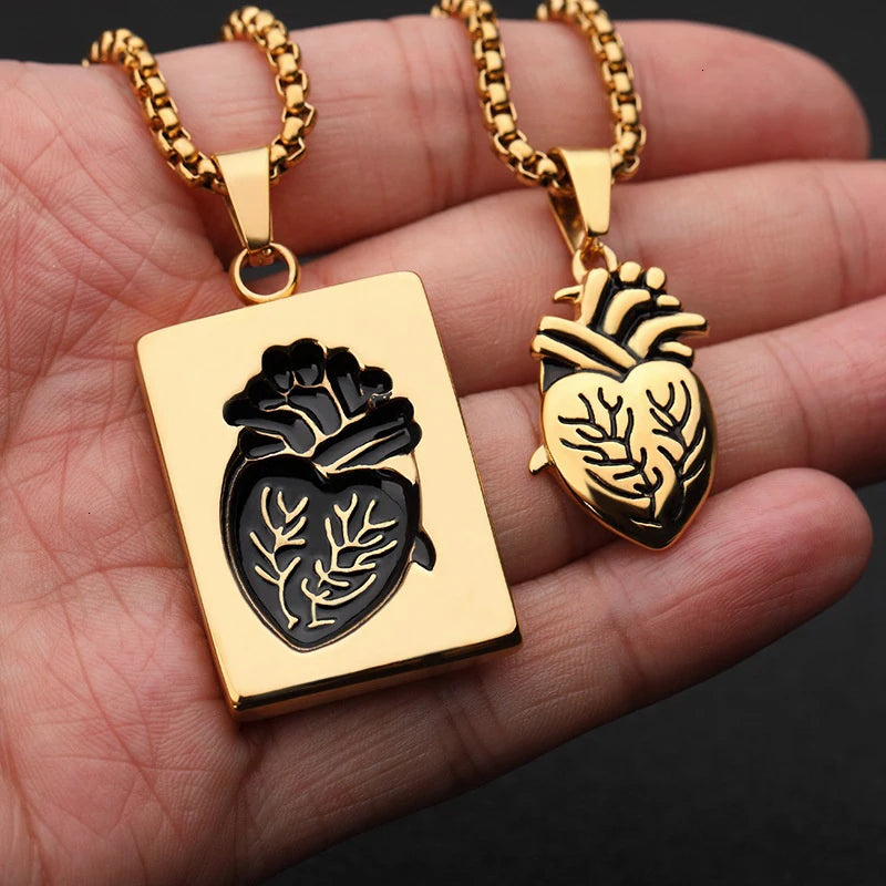 Two gold pendants with intricate designs held in a hand against a dark background