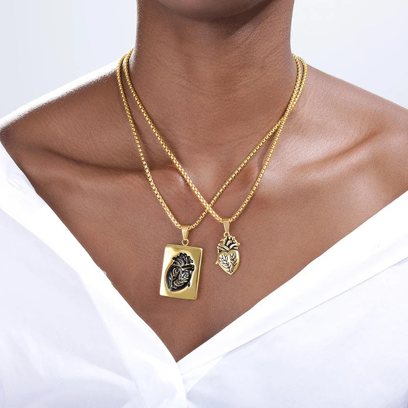 Two gold necklaces with pendants on a person wearing a white top.